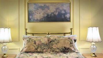 A bed with floral bedding, a painting above it, and two bedside lamps on either side.