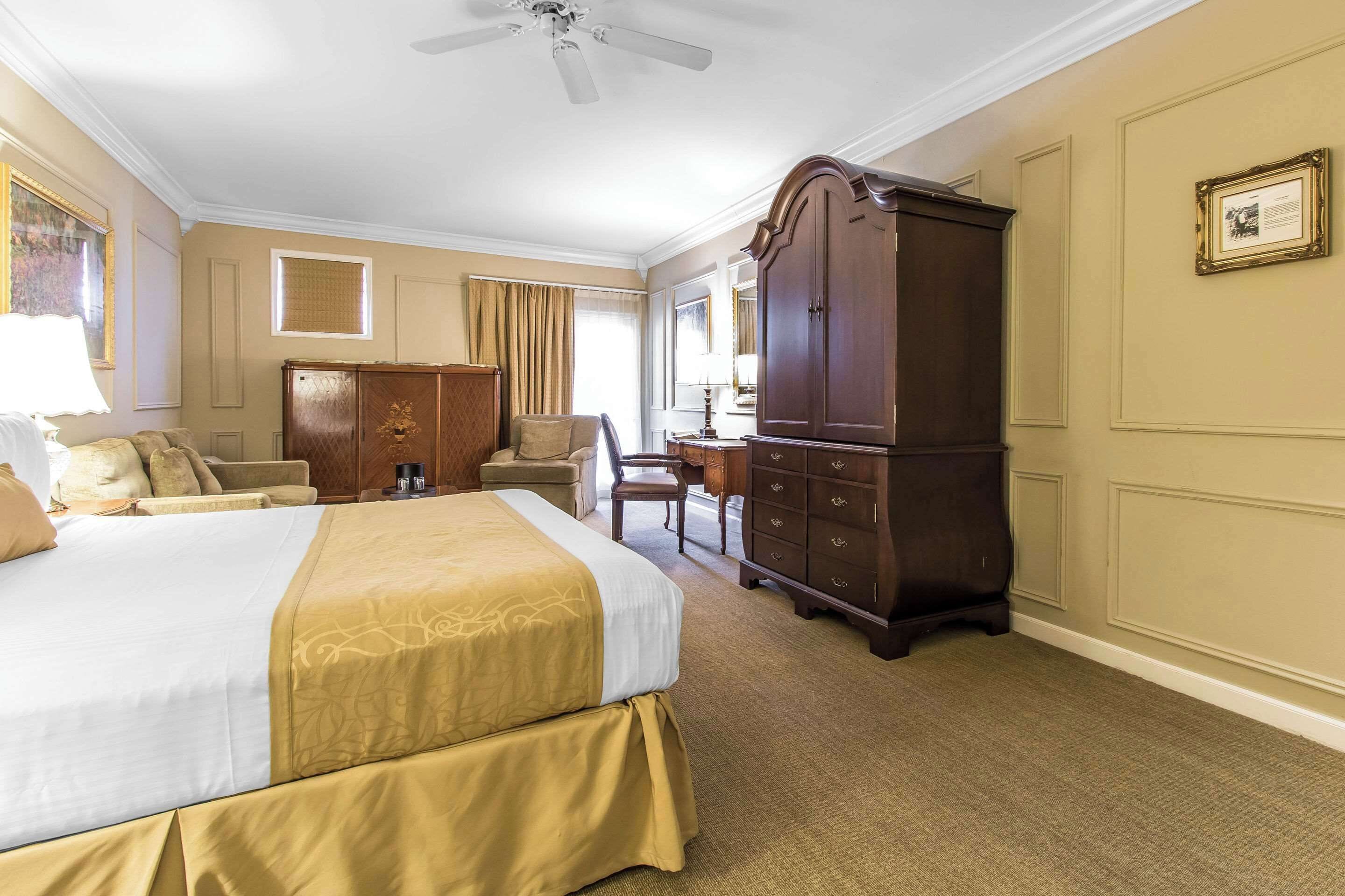 A hotel room with a large bed, a wardrobe, a desk, and a chair.