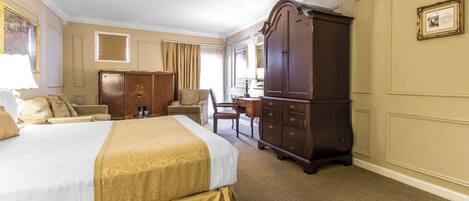 A hotel room with a large bed, a wardrobe, a desk, and a chair.