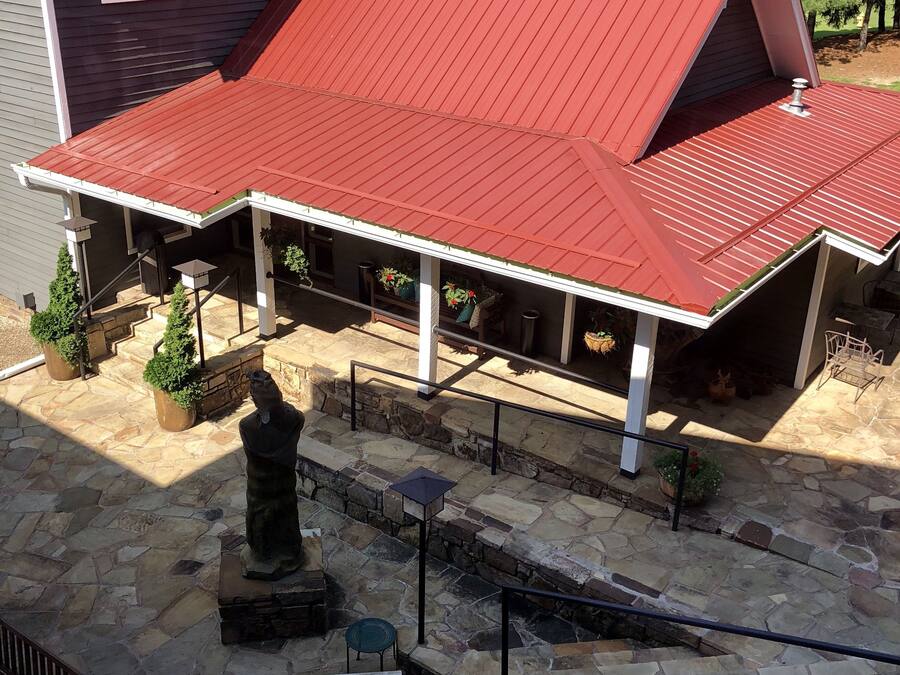 A covered outdoor area with stone flooring, a statue, and outdoor furniture.
