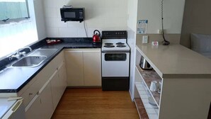 Une cuisine de taille réduite, équipée d’un évier, d’une cuisinière et d’un four à micro-ondes.