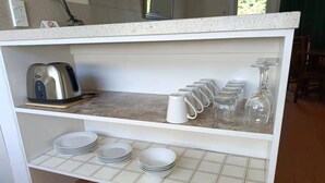 Un comptoir de cuisine avec une machine à café, de la verrerie et des assiettes empilées.