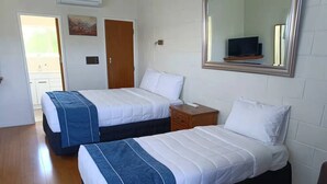 Une chambre d’hôtel avec deux lits, un plancher en bois, une petite table de chevet, un miroir et un téléviseur.