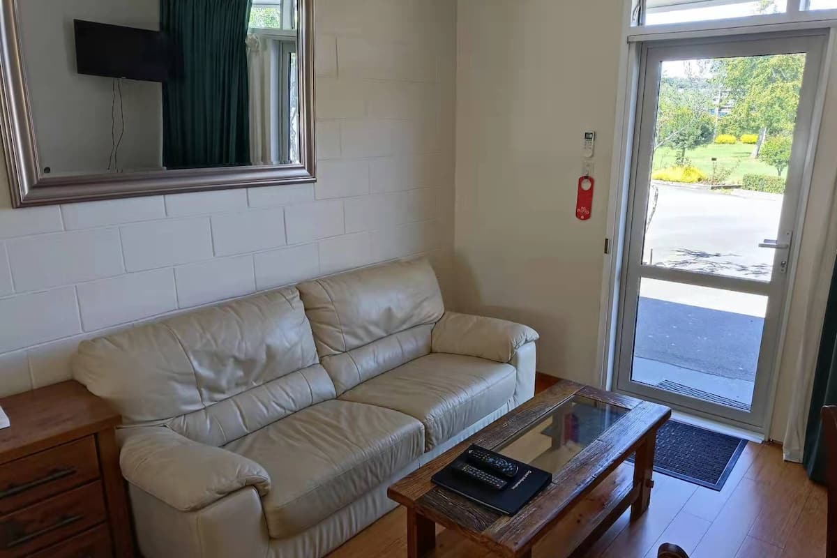 Una sala de estar con un sofá de cuero color beige, una mesa de centro de madera y un televisor montado en la pared.