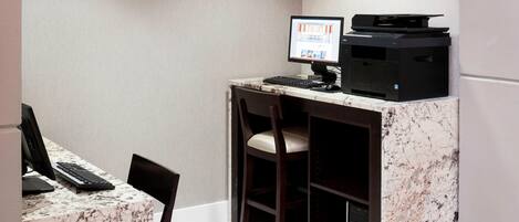 A small office space with a desktop computer, a printer, and a chair.