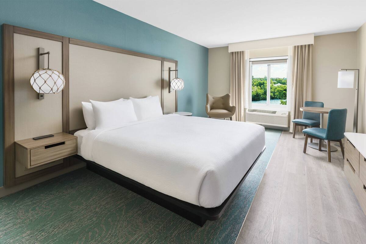 Una habitación de hotel con una cama grande, mesitas de noche, un escritorio y una silla.
