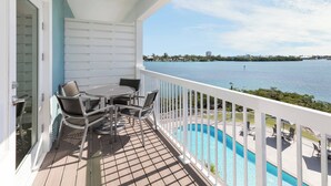 A balcony with a view of a body of water, a pool, and outdoor seating. - Fairfield Inn & Suites by Marriott Marathon Florida Keys (Marathon)
