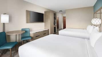 Une chambre d’hôtel avec deux lits, un bureau, une chaise, une télévision et une armoire.