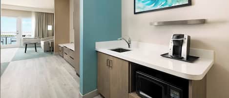 A modern kitchen with a white countertop, a coffee maker, and a microwave.