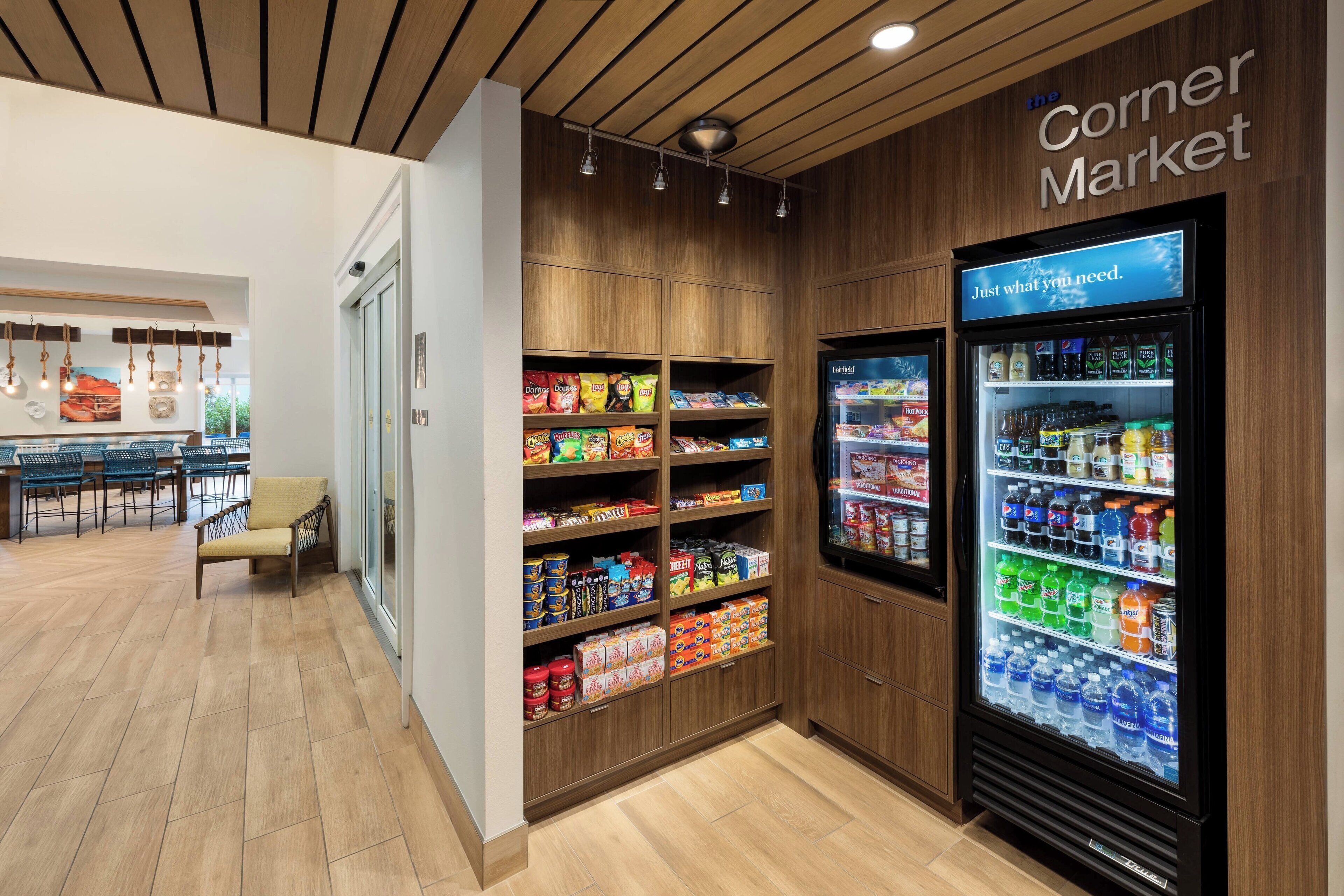 A corner market with shelves stocked with snacks and a refrigerated display case with beverages.
