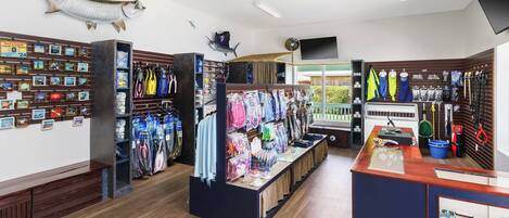 Tienda minorista con piso de madera, un mostrador de recepción y diversa mercancía, incluyendo ropa y accesorios.