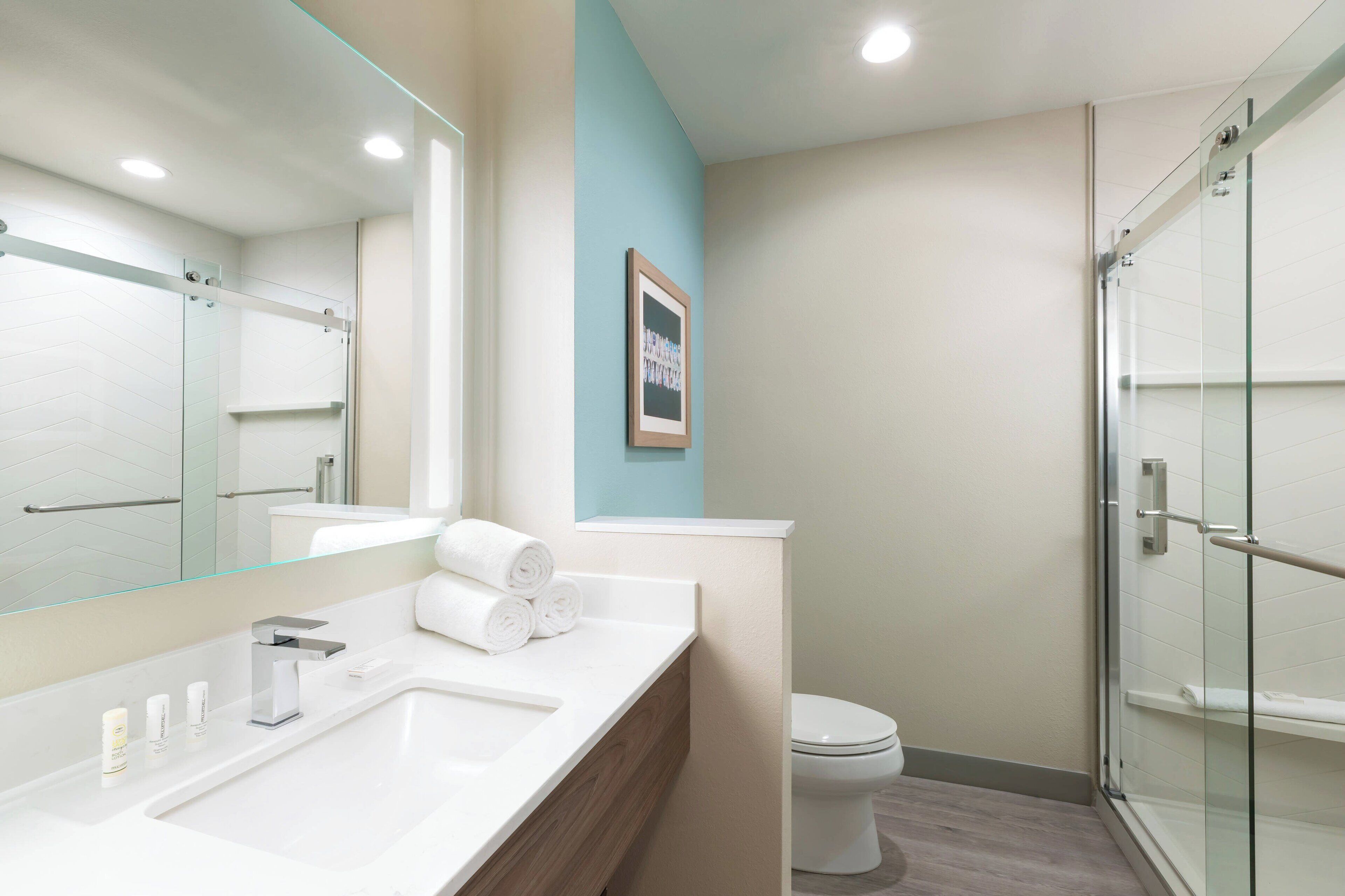 Un baño moderno con un espejo grande, un lavabo doble, un inodoro y una zona de ducha con mampara de vidrio.