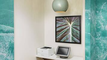 A reception desk with a printer, a monitor, and a framed artwork above.