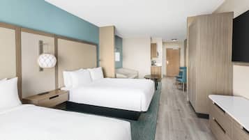 Una habitación de hotel con dos camas, un escritorio, una silla, un televisor y un minibar.