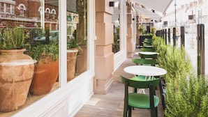 An outdoor seating area with terracotta planters and green chairs, overlooking a street with buildings. - Radisson Blu Hotel, London Bloomsbury (London)