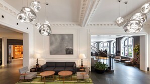 A spacious lobby with a modern sofa set, round tables, and hanging pendant lights. - Radisson Blu Hotel, London Bloomsbury (London)