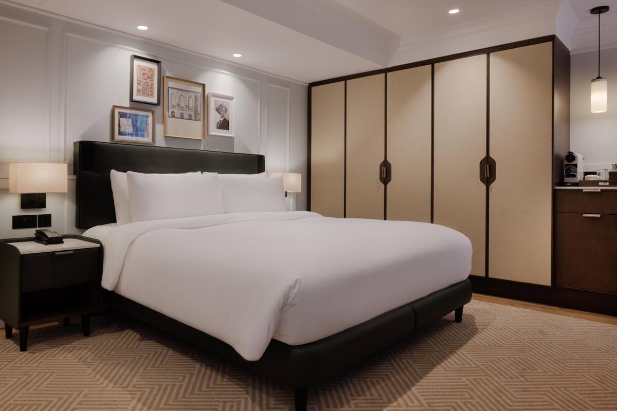 Une chambre d’hôtel avec un grand lit, une table de chevet, une armoire et des tableaux encadrés au mur.