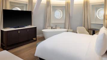 Une chambre d’hôtel moderne dotée d’un grand lit, d’une télévision à écran plat, d’une baignoire et d’un bureau.