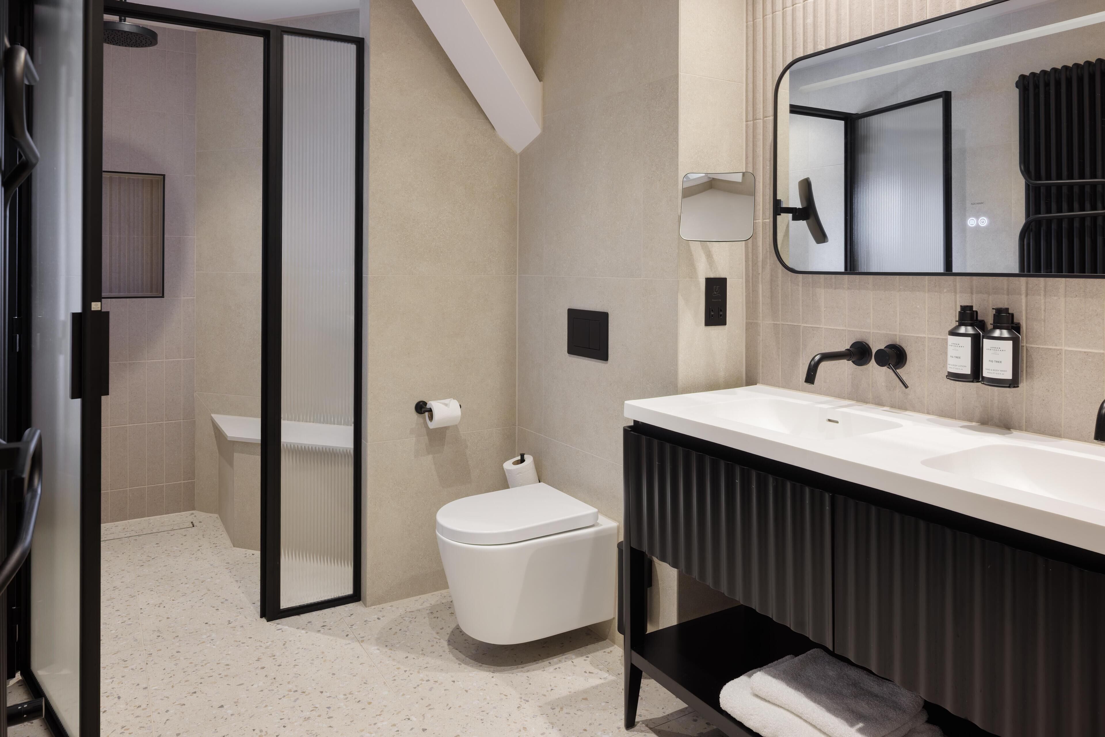 A modern bathroom with a shower, toilet, and sink.