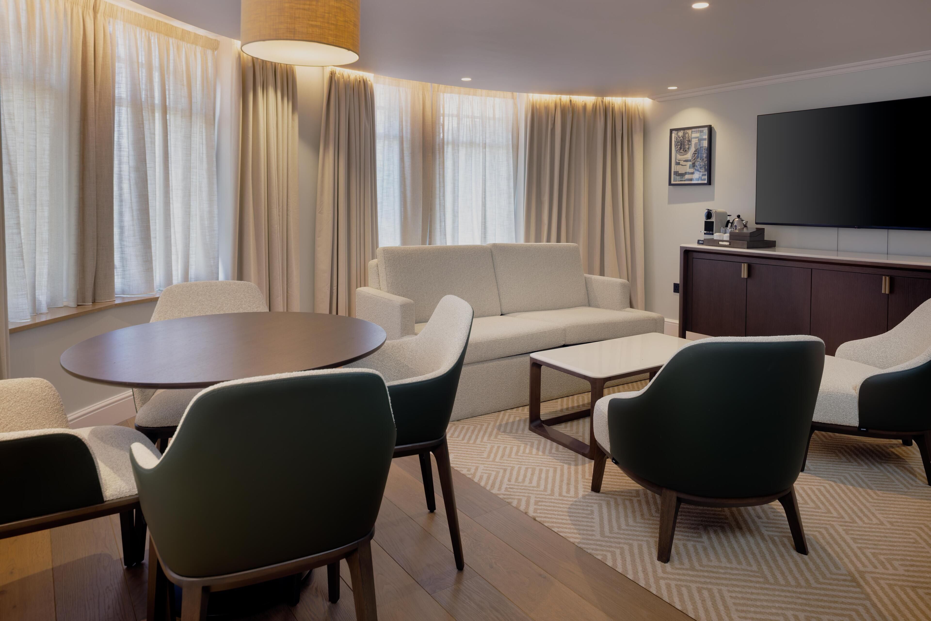 A modern living room with a sofa, chairs, a coffee table, a TV, and a cabinet.