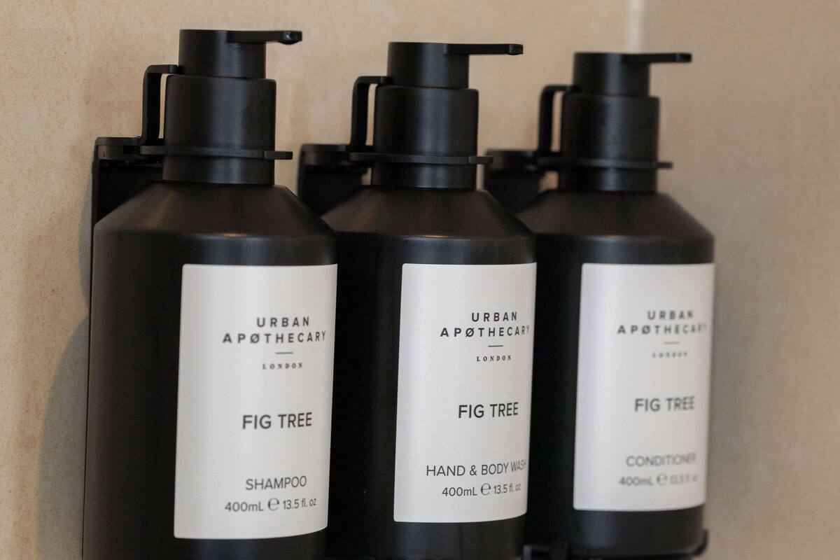 Drei schwarze Flaschen mit Urban Apothecary Fig Tree Produkten auf einer gefliesten Wand.