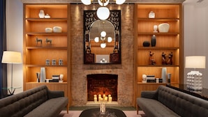 A modern living room with a fireplace, wooden shelving with decorative items, and two sofas. - Radisson Blu Hotel, London Bloomsbury (London)