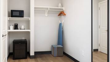 Habitación compacta con microondas, cafetera y un mueble pequeño.