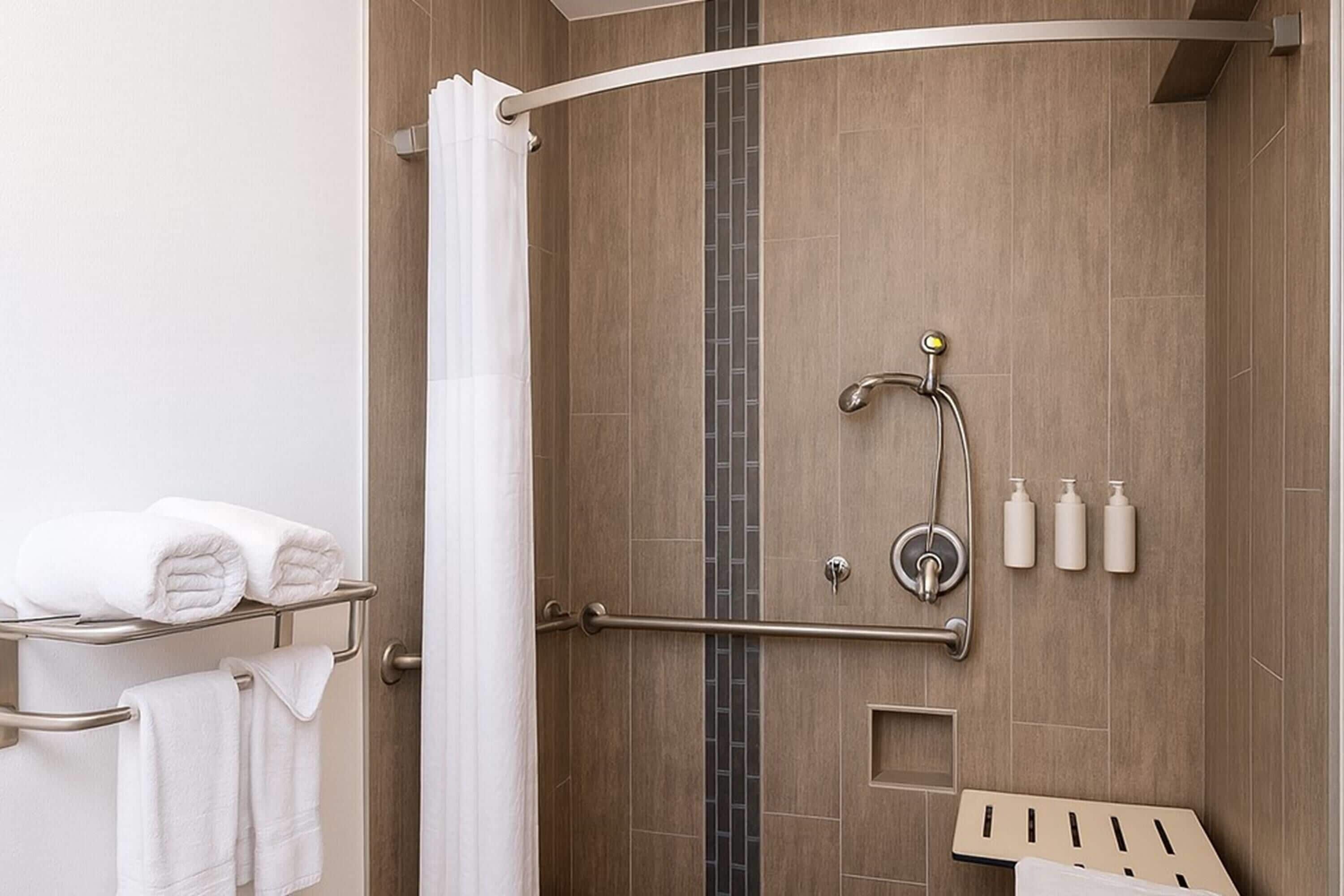 A modern shower area with a curved showerhead, a towel rack with folded towels, and a shower control panel.