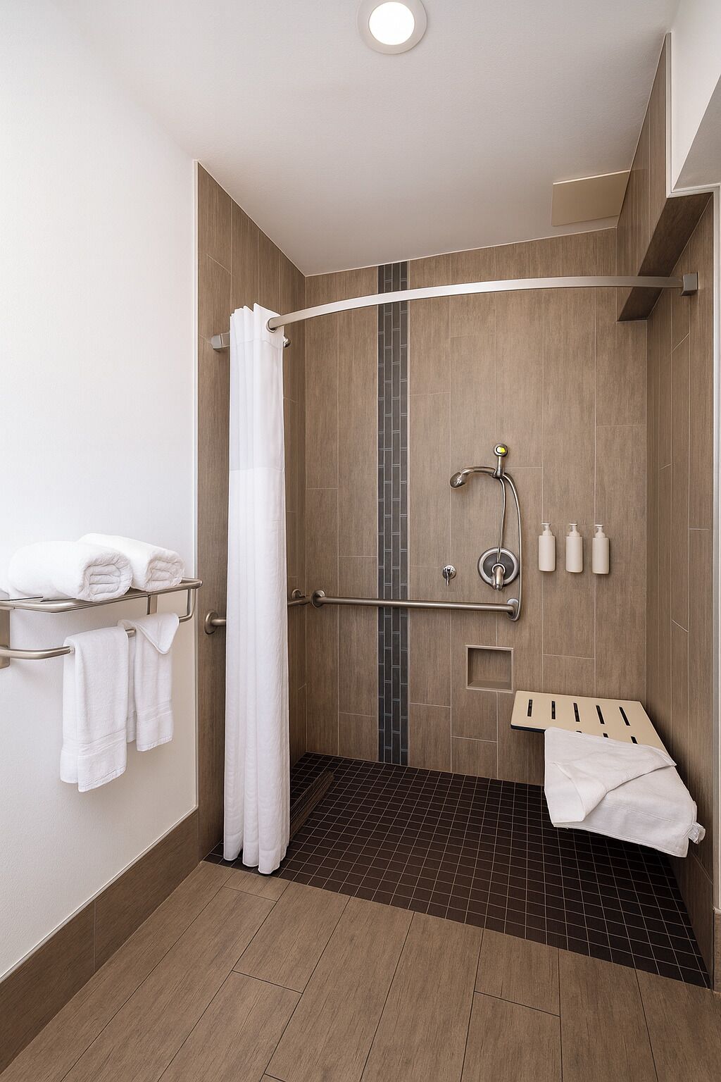A modern shower area with a curved showerhead, a towel rack, and a small shelf with toiletries.