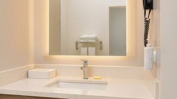 Un bagno moderno con uno specchio grande, un lavandino, un asciugacapelli e un portasciugamani.
