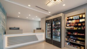 Un área de recepción moderna con mostrador, dos dispensadores de bebidas y un estante para refrigerios.