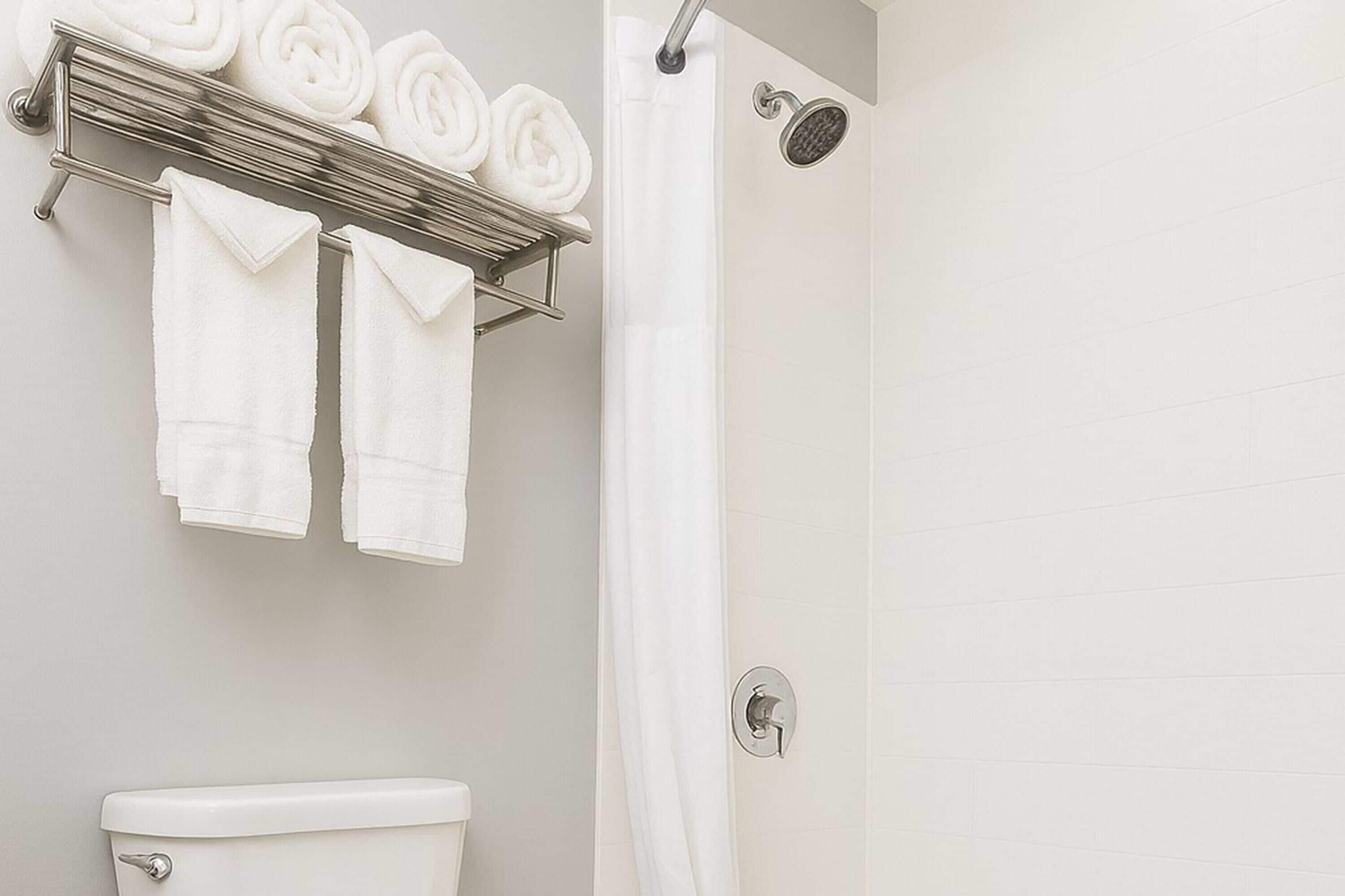 Une salle de bain avec des toilettes, un porte-serviettes avec des serviettes pliées et un rideau de douche.