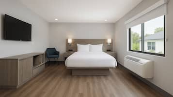 Une chambre d’hôtel moderne, dotée d’un grand lit, de tables de chevet, d’une télévision, d’un fauteuil et d’une fenêtre donnant sur l’extérieur.