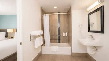 A modern bathroom with a bathtub, a sink, and a shower area. There are towels and toiletries on the wall.
