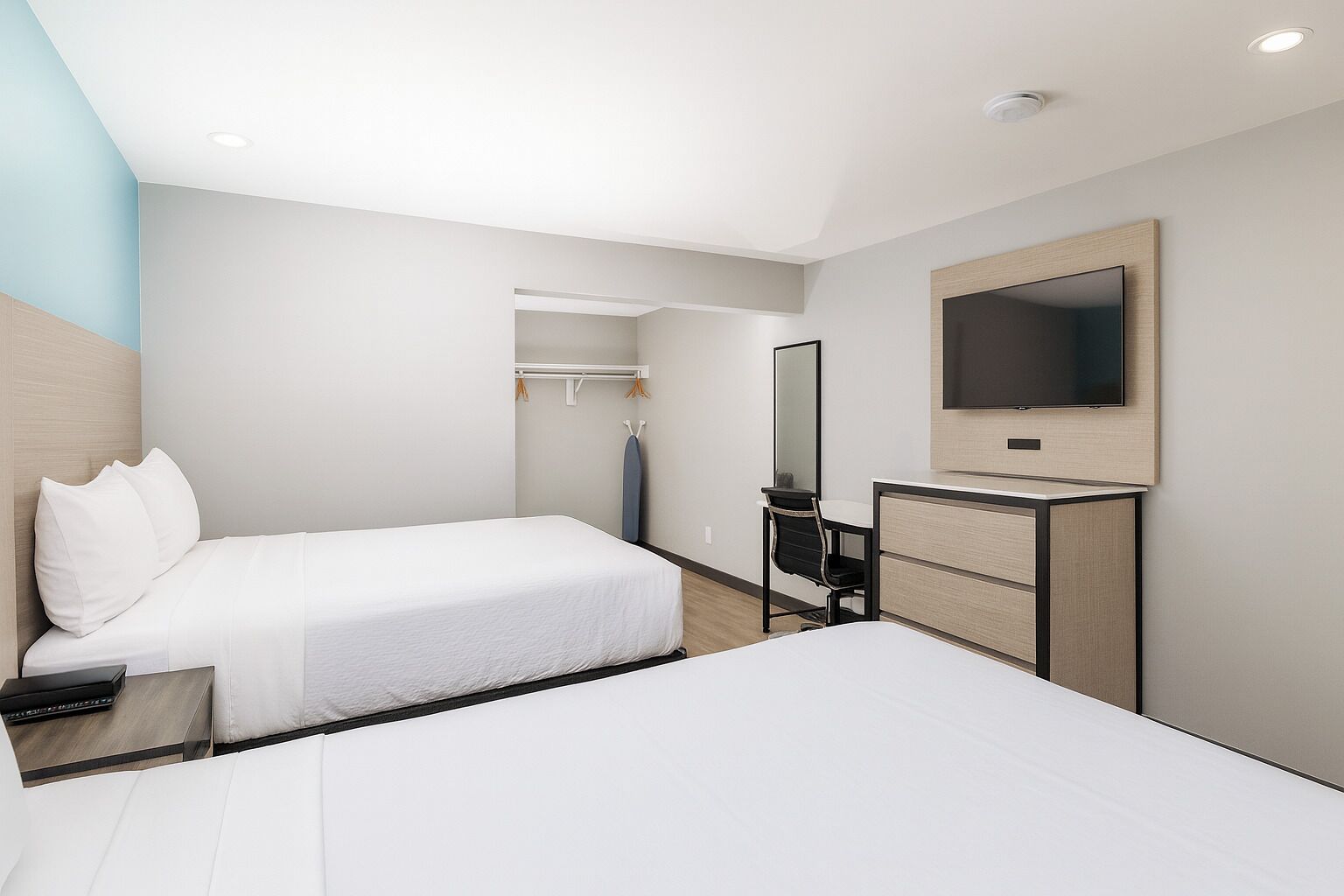 A hotel room with two beds, a desk with a chair, a TV, and a wardrobe.