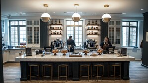 Una cocina moderna con una isla de mármol, taburetes de bar y una cafetera.