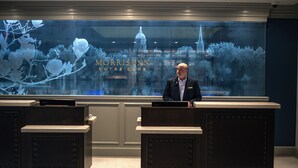 Un mostrador de recepción en el Morris Inn de Notre Dame con un amplio ventanal que muestra un paisaje urbano.