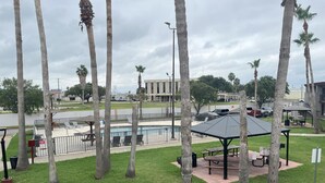 Un parque con piscina, mesas de picnic y palmeras.