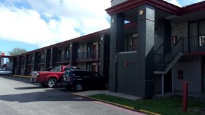 A multi-story motel with a central courtyard, featuring a red and black SUV parked in front. - Red Roof Inn Corpus Christi North - Near Downtown (Corpus Christi)