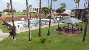Un área de piscina con sillas de descanso, un pabellón y palmeras.