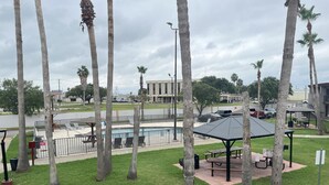 Un parque con piscina, mesas de picnic y palmeras.