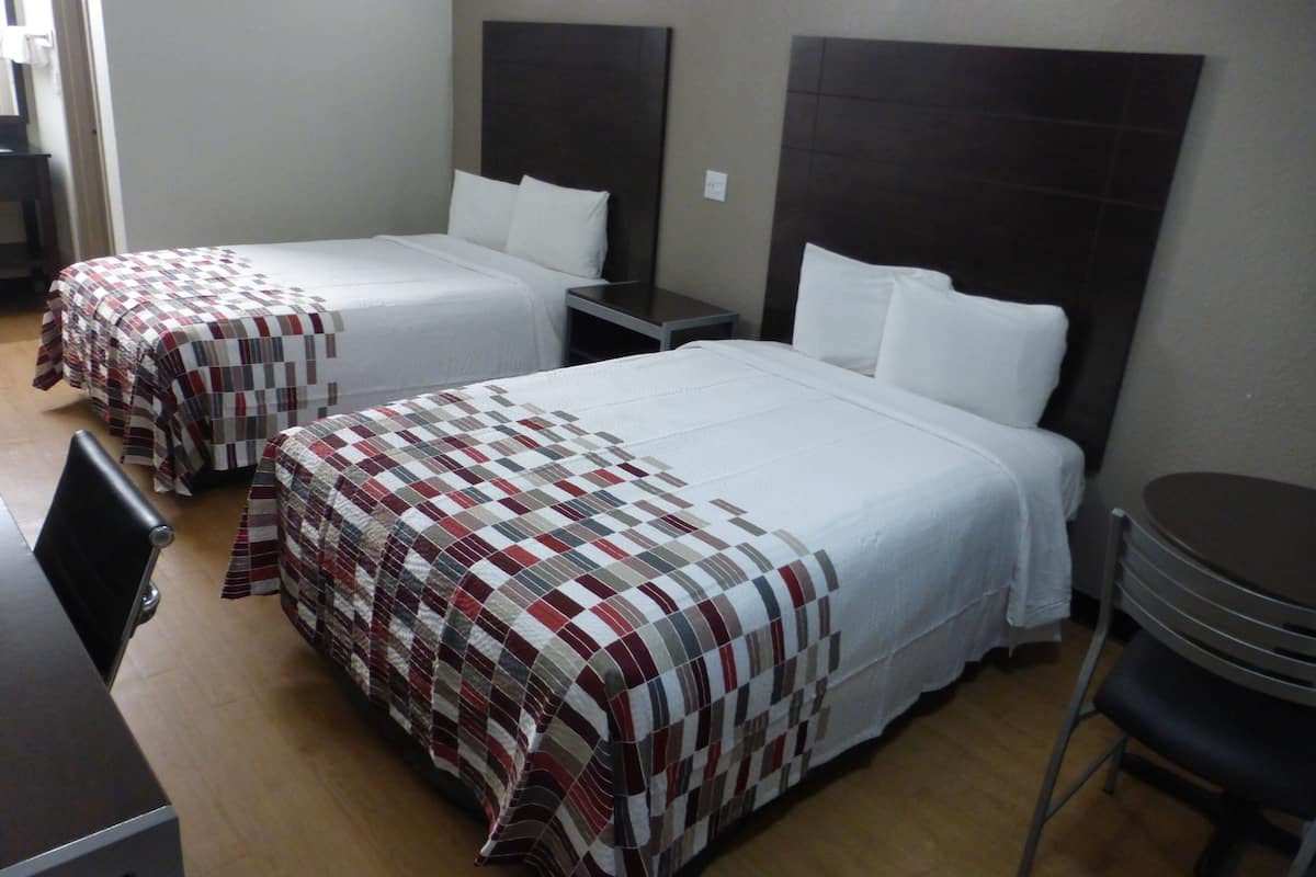 Une chambre d’hôtel comprenant deux lits simples avec des têtes de lit, un bureau et une chaise.