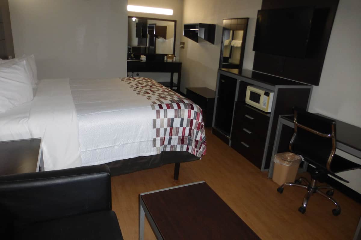 Une chambre d’hôtel équipée d’un lit, d’un bureau, d’une chaise, d’une télévision et d’un four à micro-ondes.