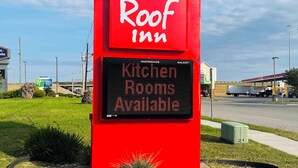 Señal de Red Roof Inn con un panel digital que indica 'Habitaciones con cocina disponibles'.