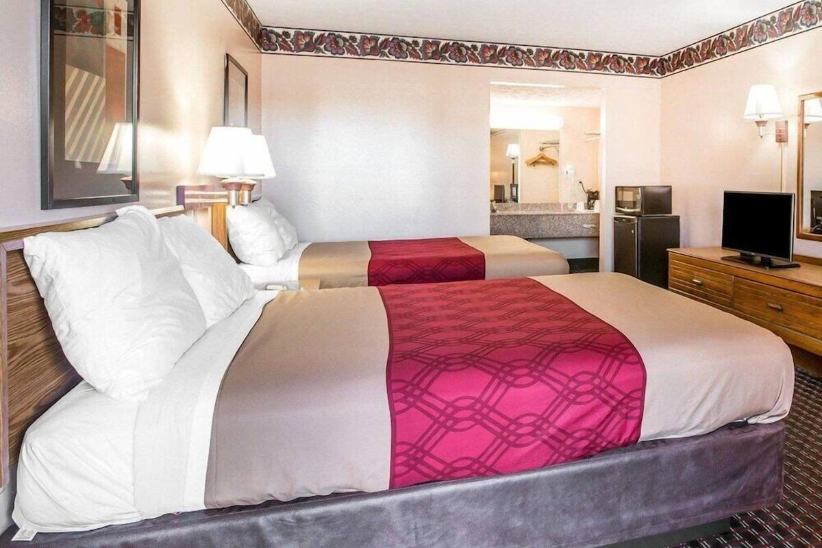 A hotel room with two beds, a television, a desk, and a mirror.