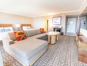 A hotel room with a sofa, a small round table, a bed, a desk, and a door leading to a bathroom. - Rio Hotel & Casino, a Destination by Hyatt Hotel (Las Vegas)