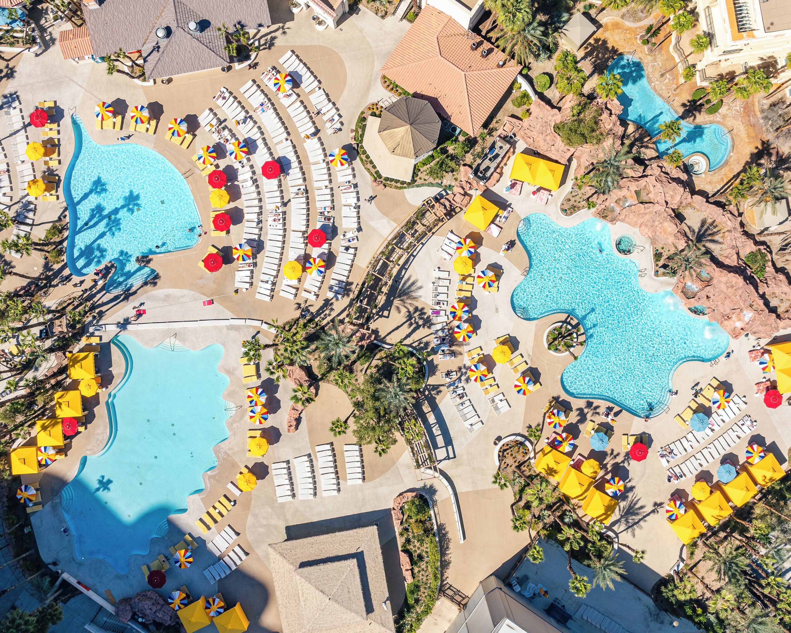 Vue aérienne d’un complexe hôtelier doté de plusieurs piscines, de chaises longues et de parasols.