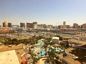 A hotel with a rooftop pool, palm trees, and a view of the Las Vegas cityscape including the Trump building and the Las Vegas Strip.