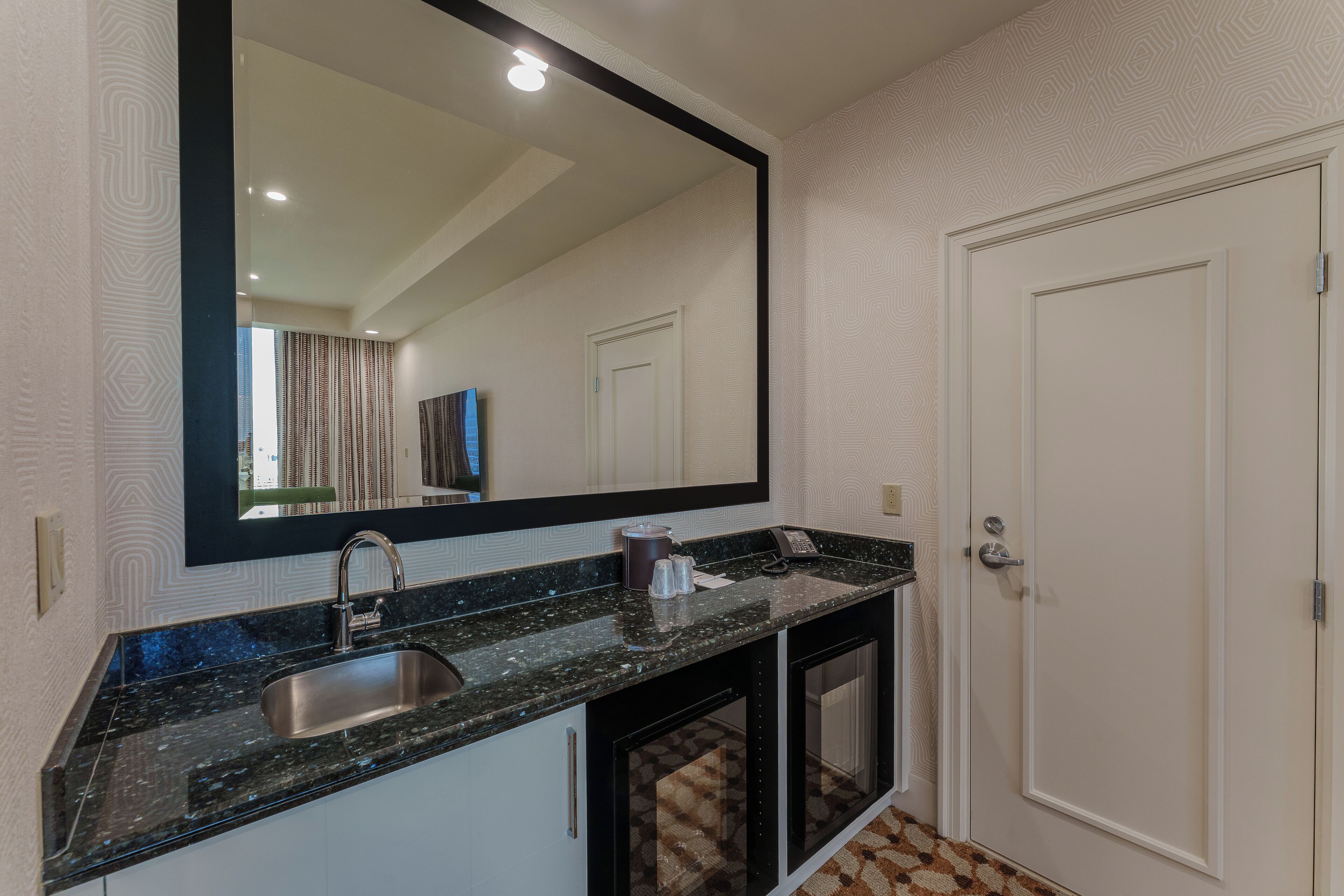 A modern bathroom with a large mirror, a sink, and a cabinet.