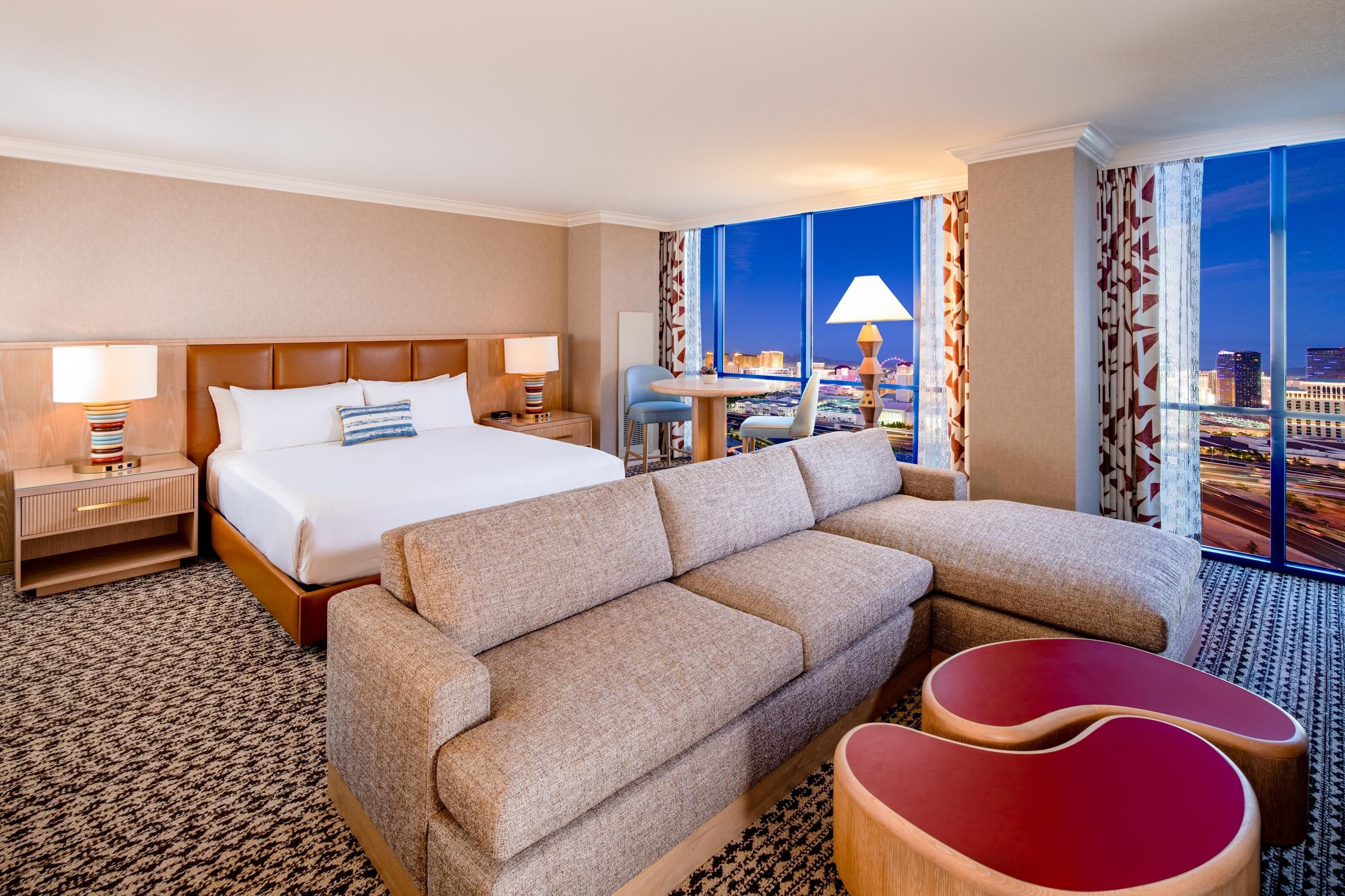 Una habitación de hotel con una cama, un sofá, una mesita y vistas a la ciudad.